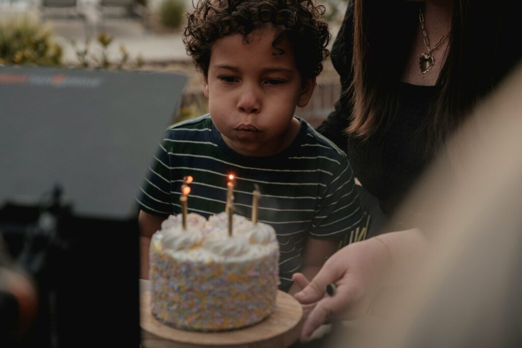Young boy blows out candles on birthday cake