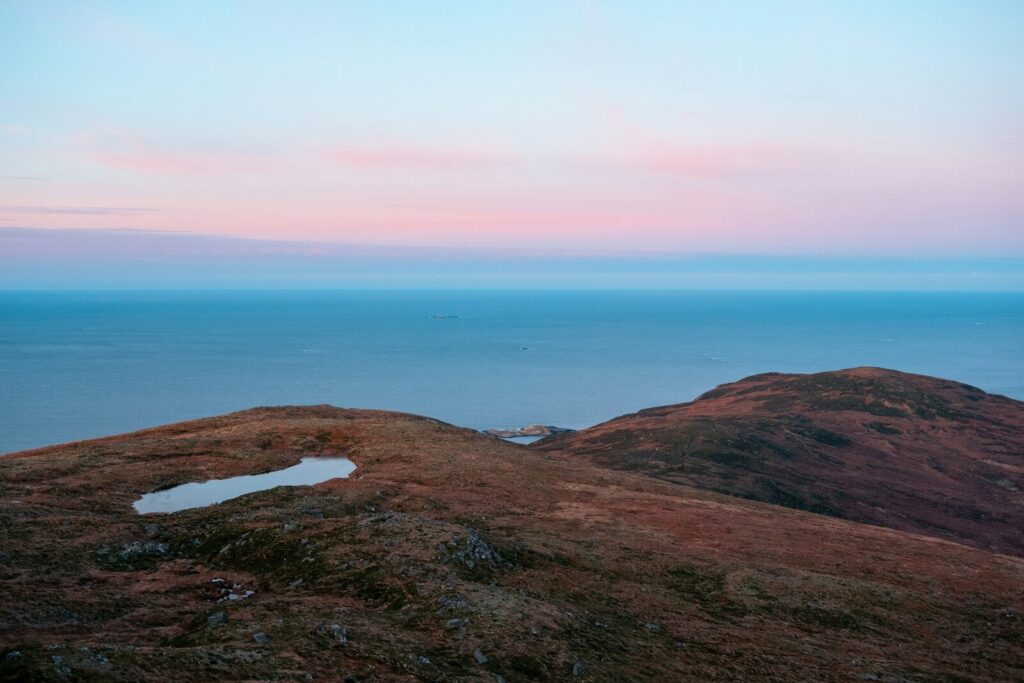 Hills and ocean under a pastel sky.